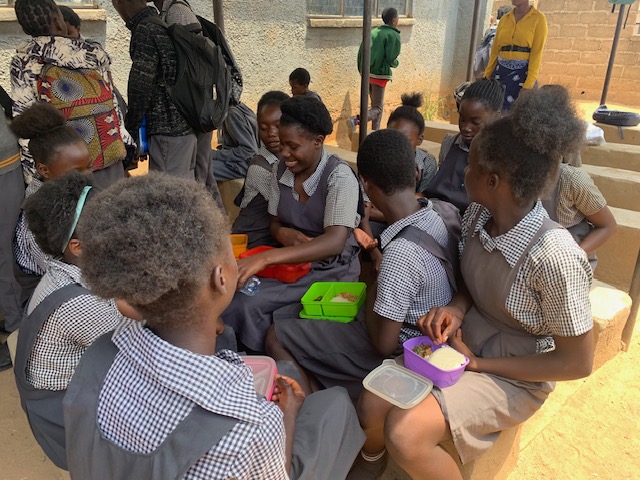 Mumba students seated under the shelter paid for by HHI