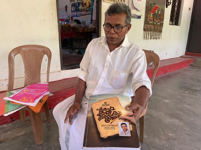 Pastor Victor Phillip with his book of published hymns